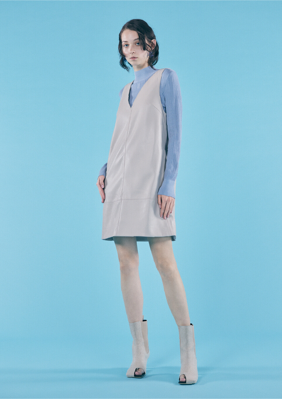青色のタートルネックと白いドレスを着て立っている女性モデルの画像
