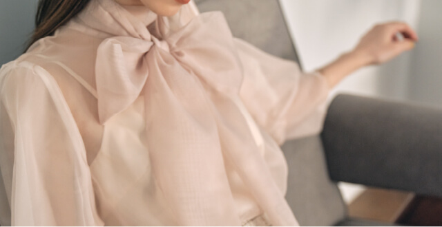 ベージュ色の服を着た女性モデルの上半身のリボンのUP画像