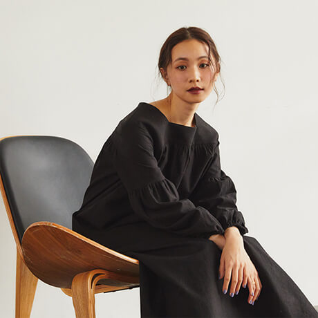 黒いドレスを着て椅子に座ってる女性モデル画像